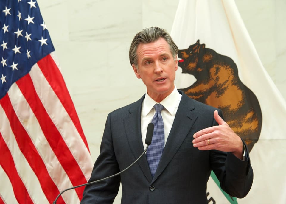 California Governor Gavin Newsom signing legislation at a desk in Sacramento