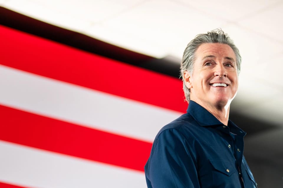 Governor Gavin Newsom at a signing ceremony for legislation, with California and cryptocurrency imagery in the background